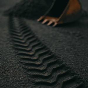 Däckspår från anläggningsmaskin på grusväg – symbol för maskinförares arbetsmiljö.